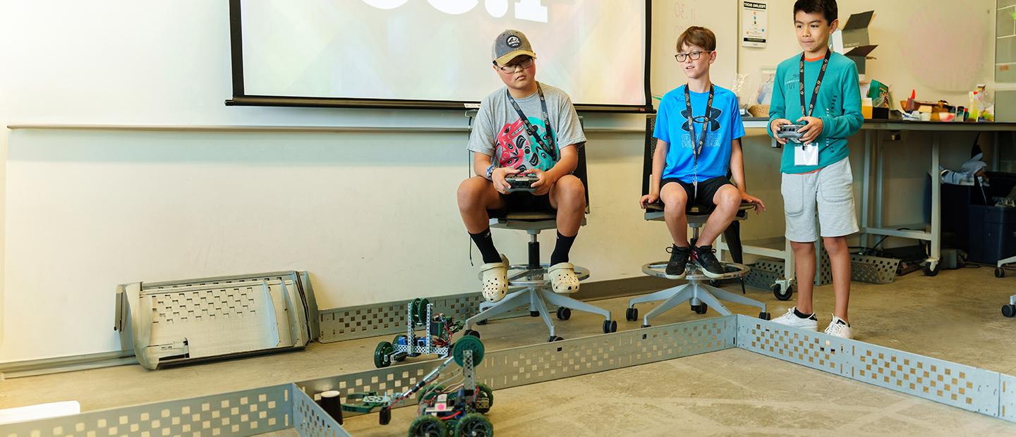 Three young boys using remote controlled robots